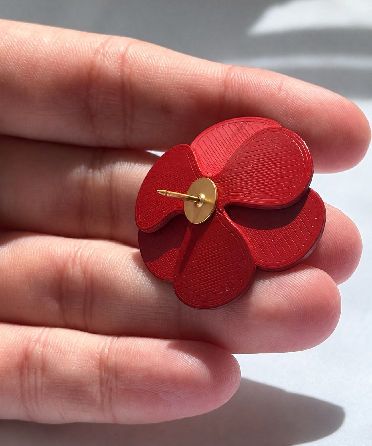 Close-up of the red anemone pin's textured petals, held in hand