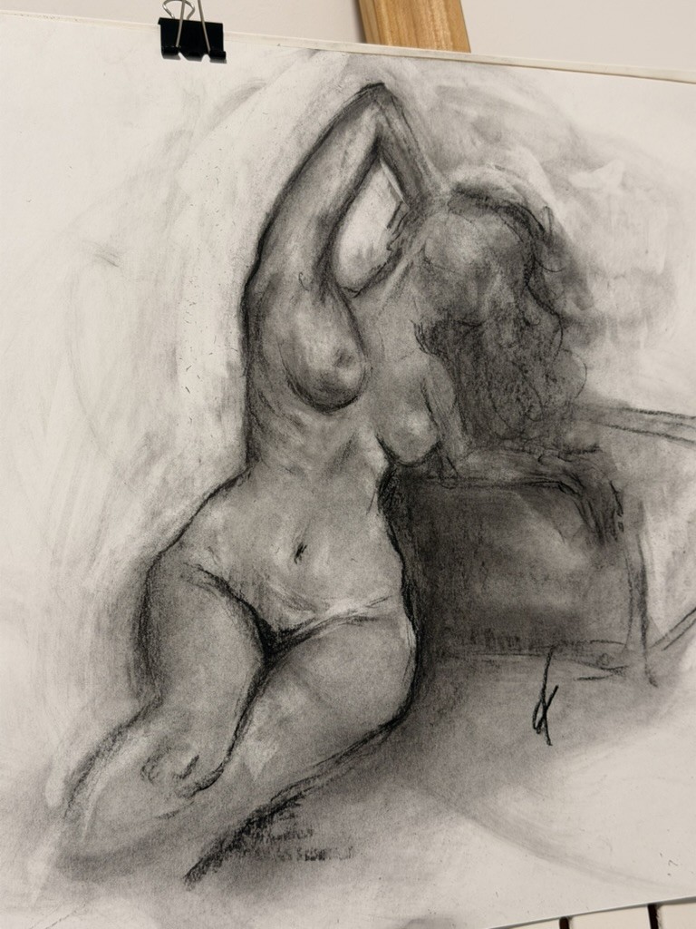 Open category: Charcoal — charcoal drawing of a seated nude figure with arms raised over her head, clipped to an easel