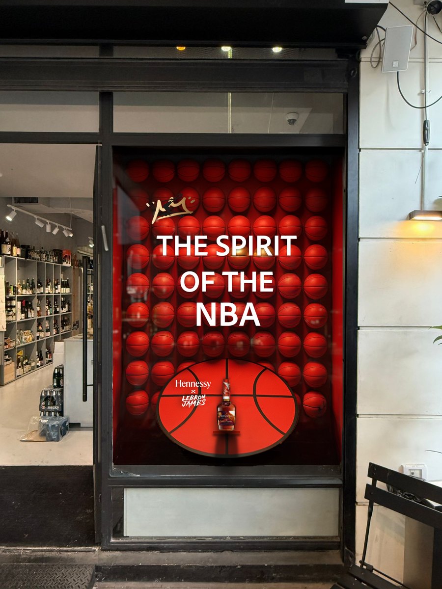 Window display concept: a red wall of basketballs, “The Spirit of the NBA” lettering and a court-shaped stand holding the Hennessy × LeBron James bottle