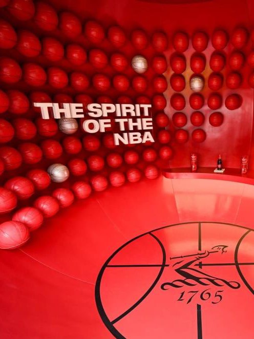 Hennessy's red Spirit of the NBA brand space, a wall of basketballs around a court-marked floor