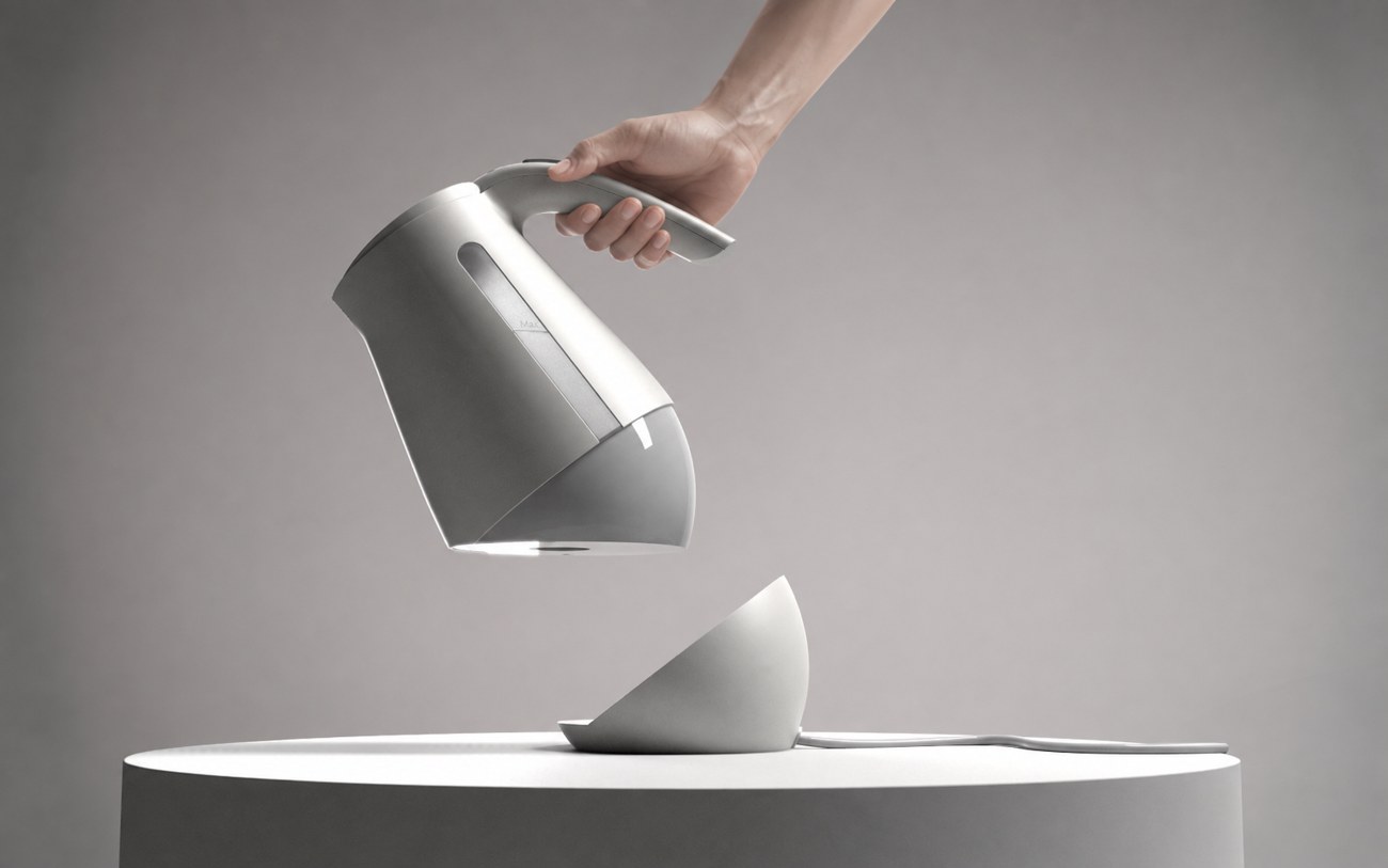 A hand lifting The Sinking Kettle off its base