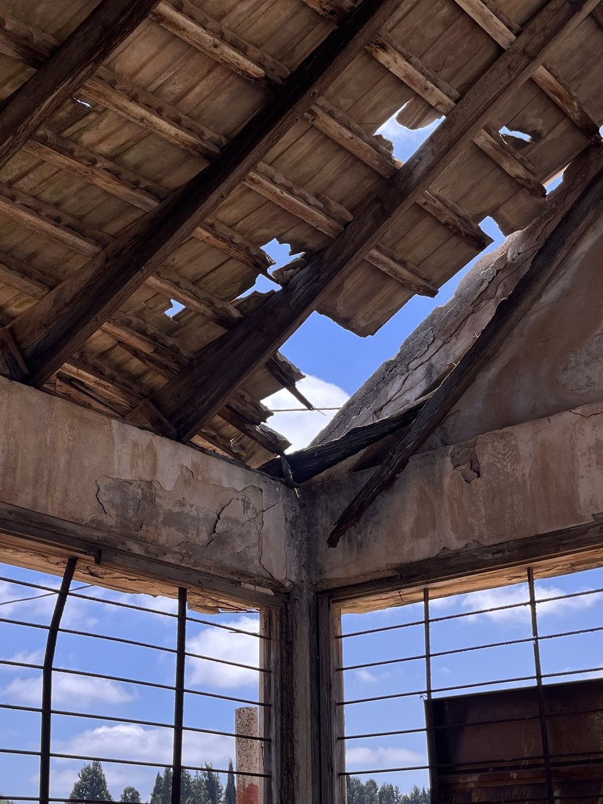 Open series: Abandoned Structure in an Orchard — broken roof beams and a barred window inside a ruined packing house